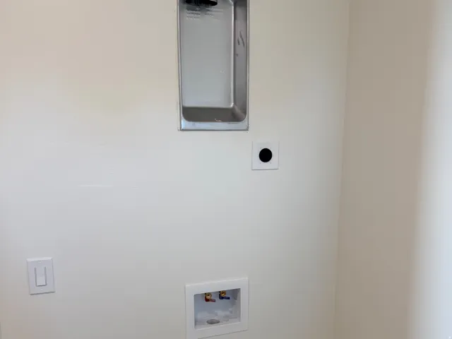 Dedicated laundry area featuring a wall-mounted dryer vent, washing machine hookups, and neutral wall paint