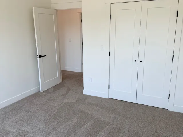 Neutral-toned carpeted flooring with white baseboards throughout