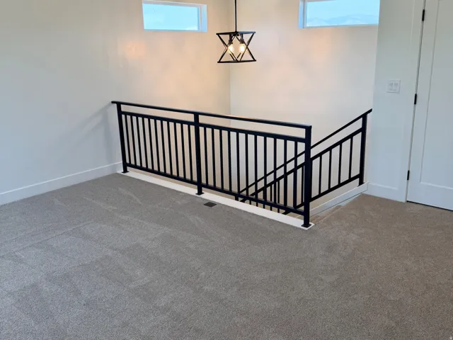 Upper level landing with gray carpet flooring and contemporary black metal railing