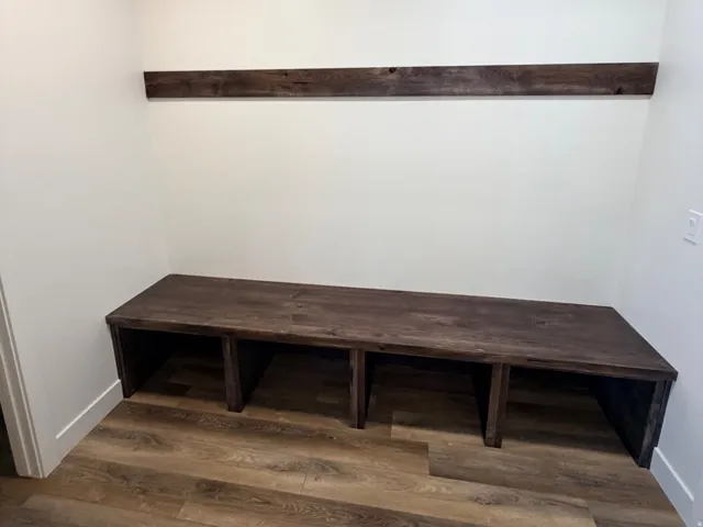 Built-in wood-finish bench with integrated storage cubbies, complemented by an overhead wood-finish wall accent