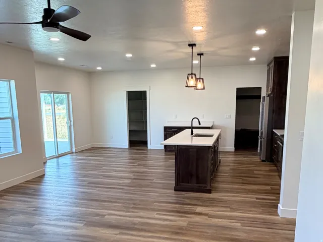Open-concept living area with wood-finish flooring, recessed lighting, and a modern ceiling fan