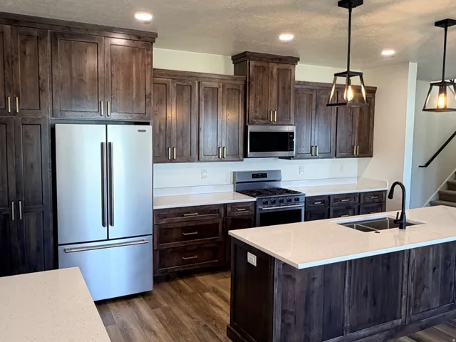 Modern kitchen featuring dark wood cabinetry, light-toned countertops, and wood-finish flooring