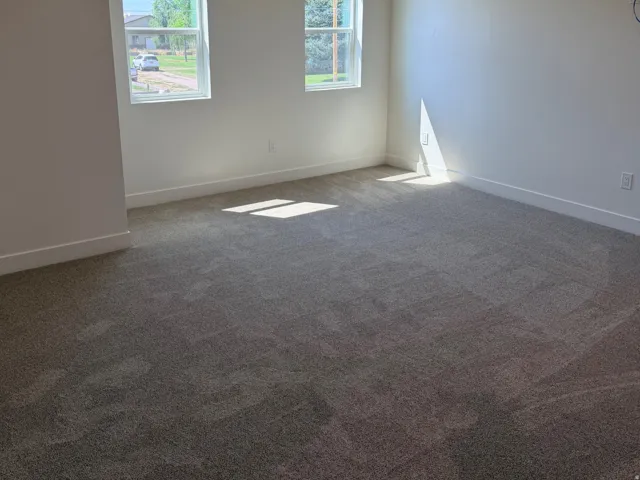 Spacious room featuring neutral carpeting, recessed ceiling lighting, and two windows providing exterior views