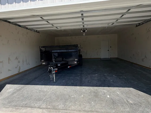 Spacious garage with a concrete floor, overhead door, and exposed framing