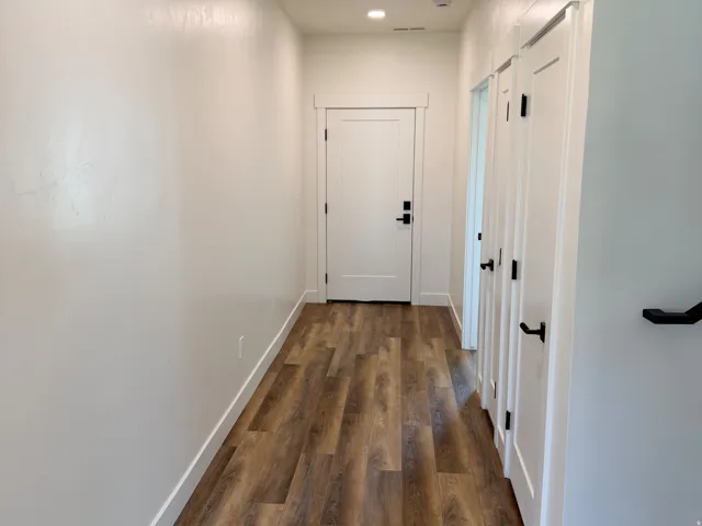 Hallway featuring wood-finish flooring, recessed lighting, and white baseboards