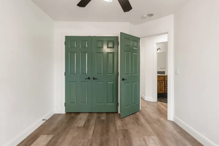 Bedroom featuring wood-finish flooring, white walls, and a ceiling fan