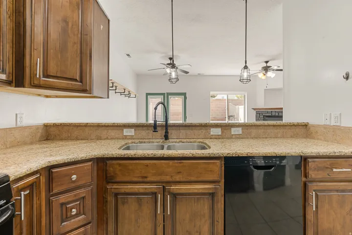 Kitchen featuring rich wood cabinetry, granite-style countertops, and a double-basin stainless steel sink with a matte black faucet
