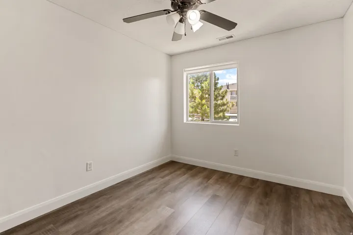 Interior room featuring wood-finish flooring, white walls, and a white trim baseboard