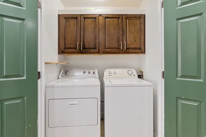 Dedicated laundry area with rich wood cabinetry, white walls, and a small built-in shelf