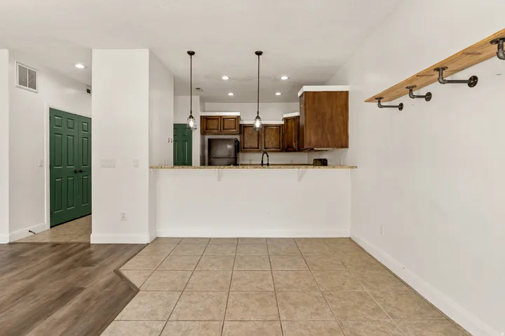 Open-concept kitchen featuring wood cabinetry, pendant lighting, and a breakfast bar with a light-colored countertop