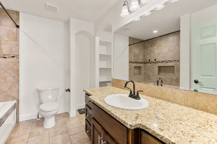 Bathroom featuring a dark wood-finish vanity with a granite countertop, undermount sink, and matte black faucet