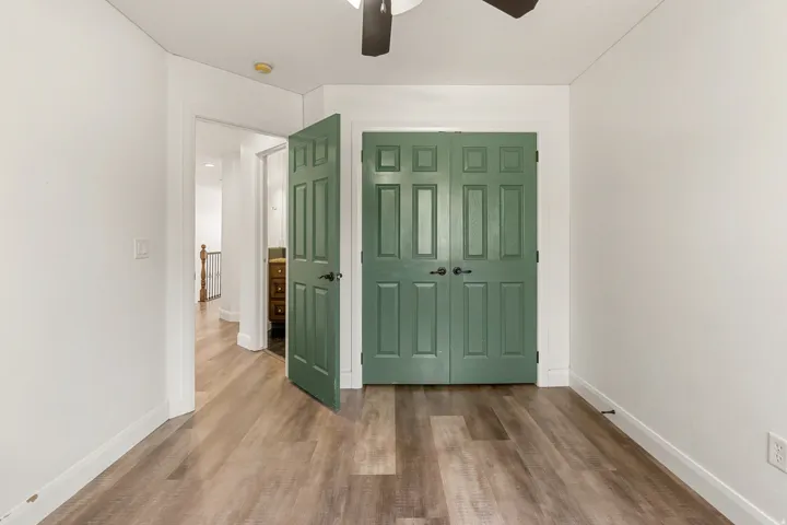 Interior room featuring wood-finish flooring, white walls, and a ceiling fan