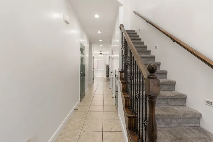 Staircase featuring dark wood handrails, wrought iron balusters, and carpeted treads
