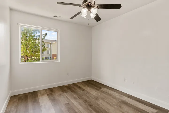 Room with wood-finish flooring, white baseboards, and a window with white trim