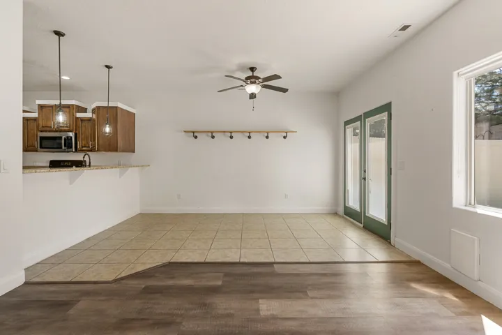 Open concept living area featuring a breakfast bar with pendant lighting, a ceiling fan, and dual-pane glass doors