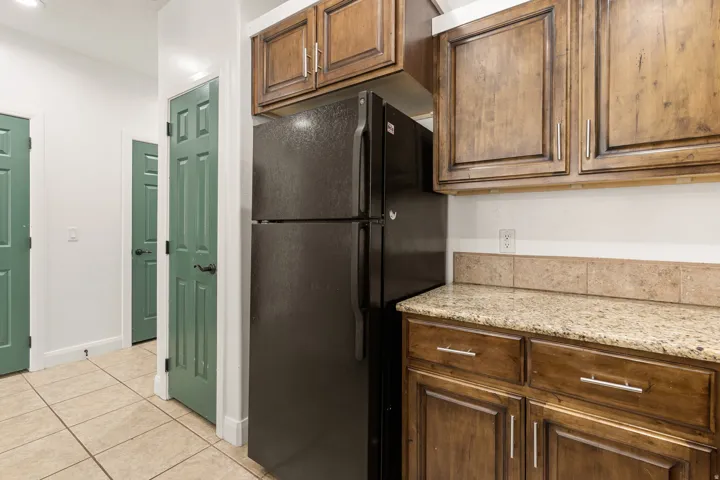 Kitchenette area featuring wood cabinetry, granite-finish countertops, and a tiled backsplash