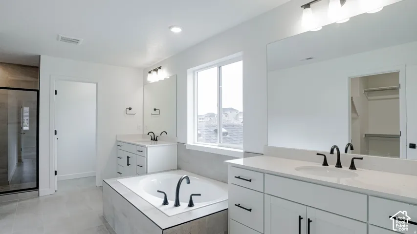 Spa-inspired primary bathroom featuring dual vanities with white cabinetry, quartz countertops, and matte black faucet fixtures