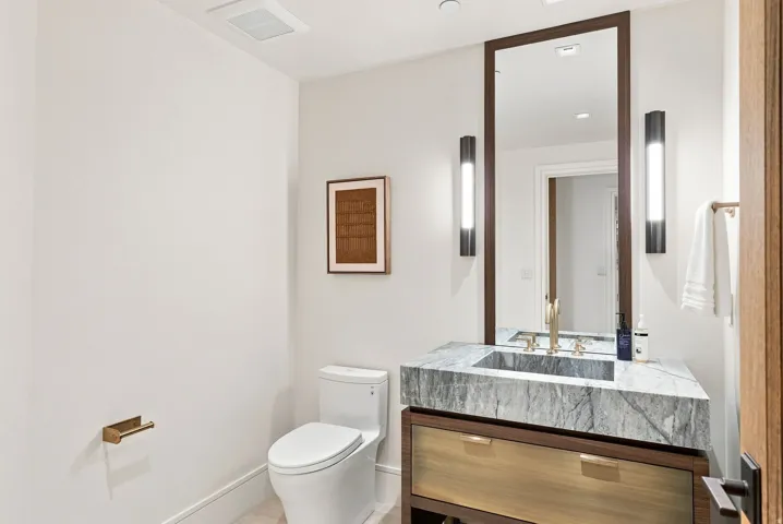Modern bathroom featuring a floating wood-finish vanity with a marble-look countertop, rectangular vessel sink, and matte black wall-mounted sconces
