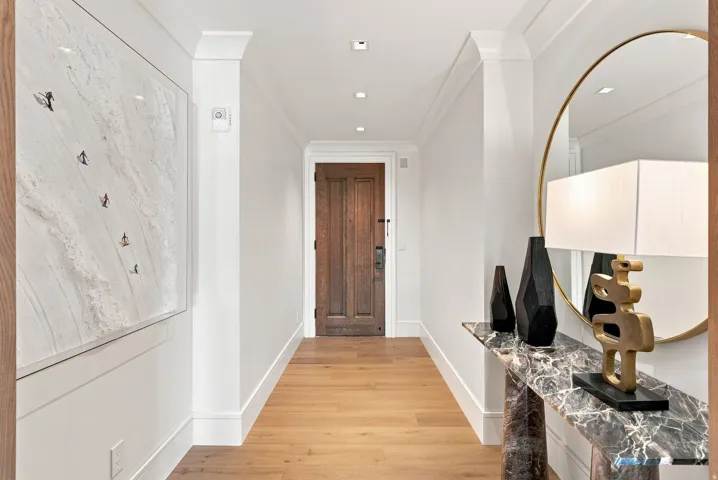 Elegant hallway showcasing wide-plank wood-finish flooring, crisp white walls, and recessed ceiling lighting