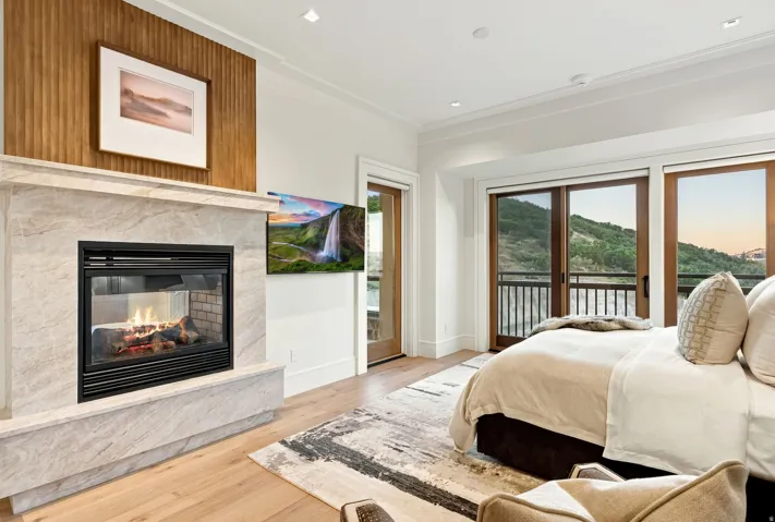 Light wood-finish flooring complements a fireplace featuring a stone surround and hearth