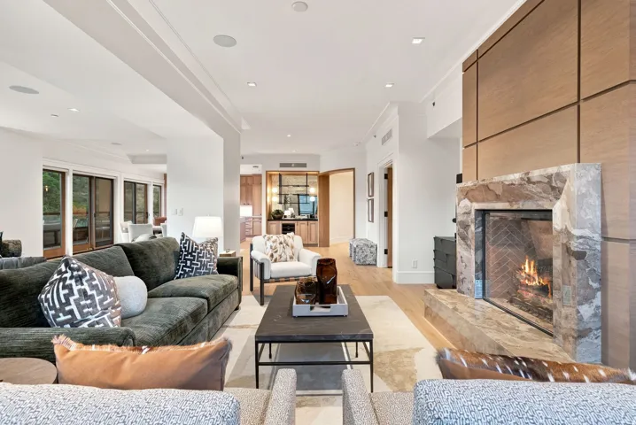 Sophisticated open-concept living space featuring a gas fireplace with stone surround, recessed ceiling lighting, and wood-finish flooring throughout