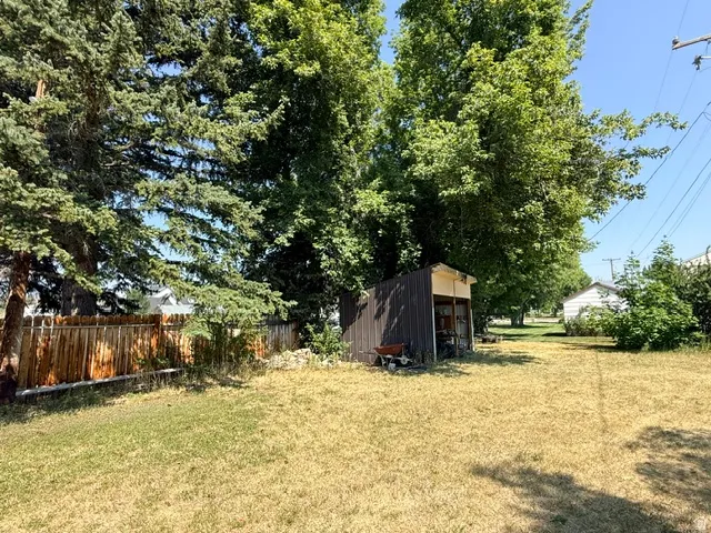 Spacious grounds featuring mature shade trees, open lawn area, and a rustic outbuilding