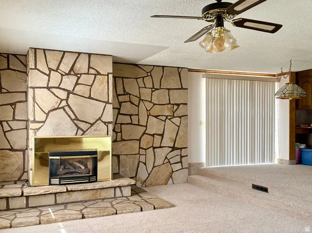 Spacious living room anchored by a striking stone fireplace with brass surround and gas insert