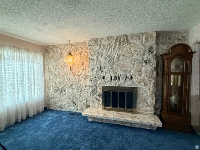 Elegant formal living room anchored by a striking textured stone fireplace with dark inset hearth and decorative mantel