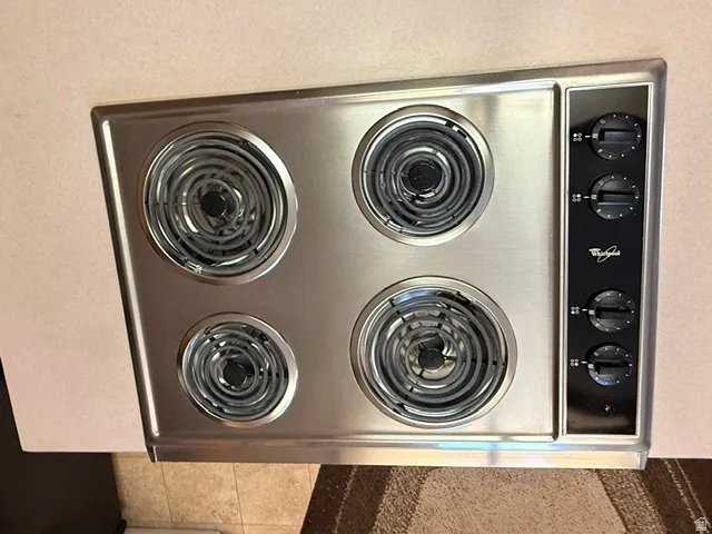 Stainless steel cooktop with four coil burners and side-mounted controls
