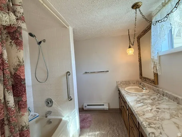 Bathroom featuring a tub/shower combination with white tiled surround, a chrome grab bar, and a single vanity with a white basin and stone-finish countertop