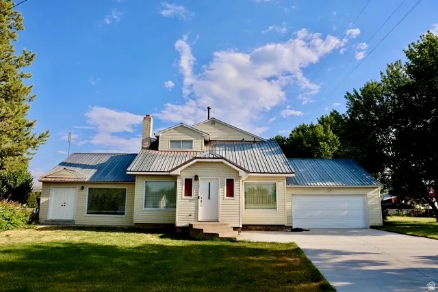 Charming single-story residence featuring a distinctive metal roof with multiple pitched peaks, cream exterior siding, and a covered front entry