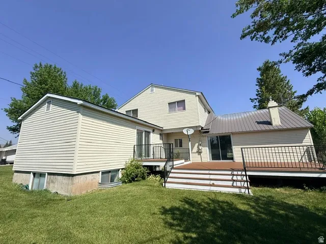 Charming split-level home featuring vinyl siding exterior, multiple roof lines with metal accenting, and a spacious manicured lawn