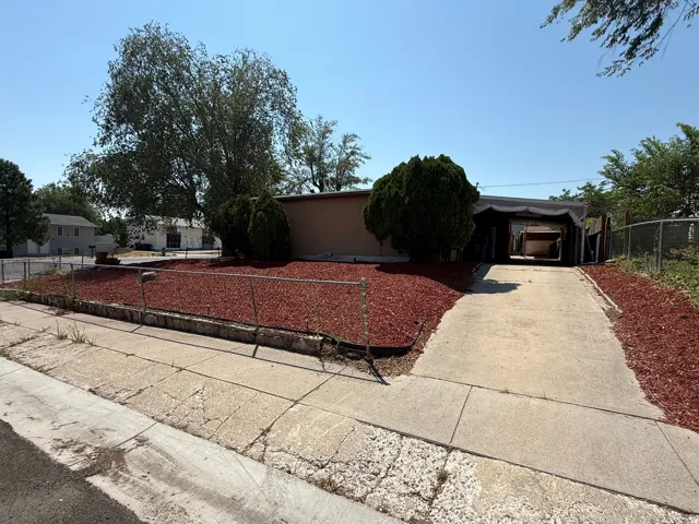 Charming single-story home situated on a landscaped lot with mature trees and decorative red rock hardscaping