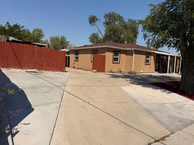 Spacious front-facing driveway with concrete surface and mature shade trees