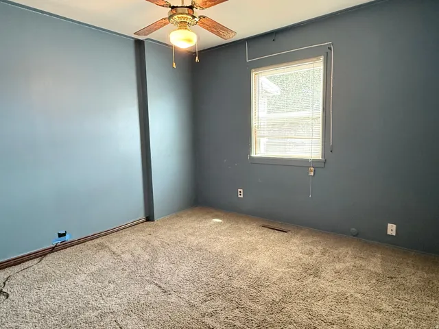 Carpeted room featuring a ceiling fan with light fixture, a window with blinds, and painted walls