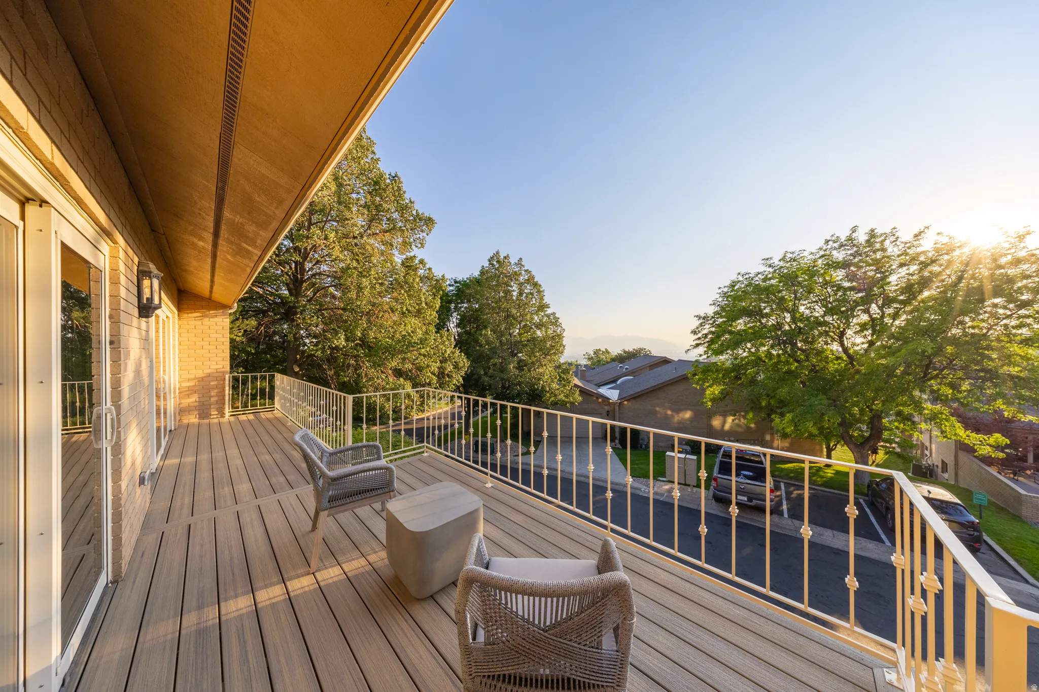 Expansive outdoor deck featuring composite wood-finish flooring, a decorative metal railing, and brick exterior siding
