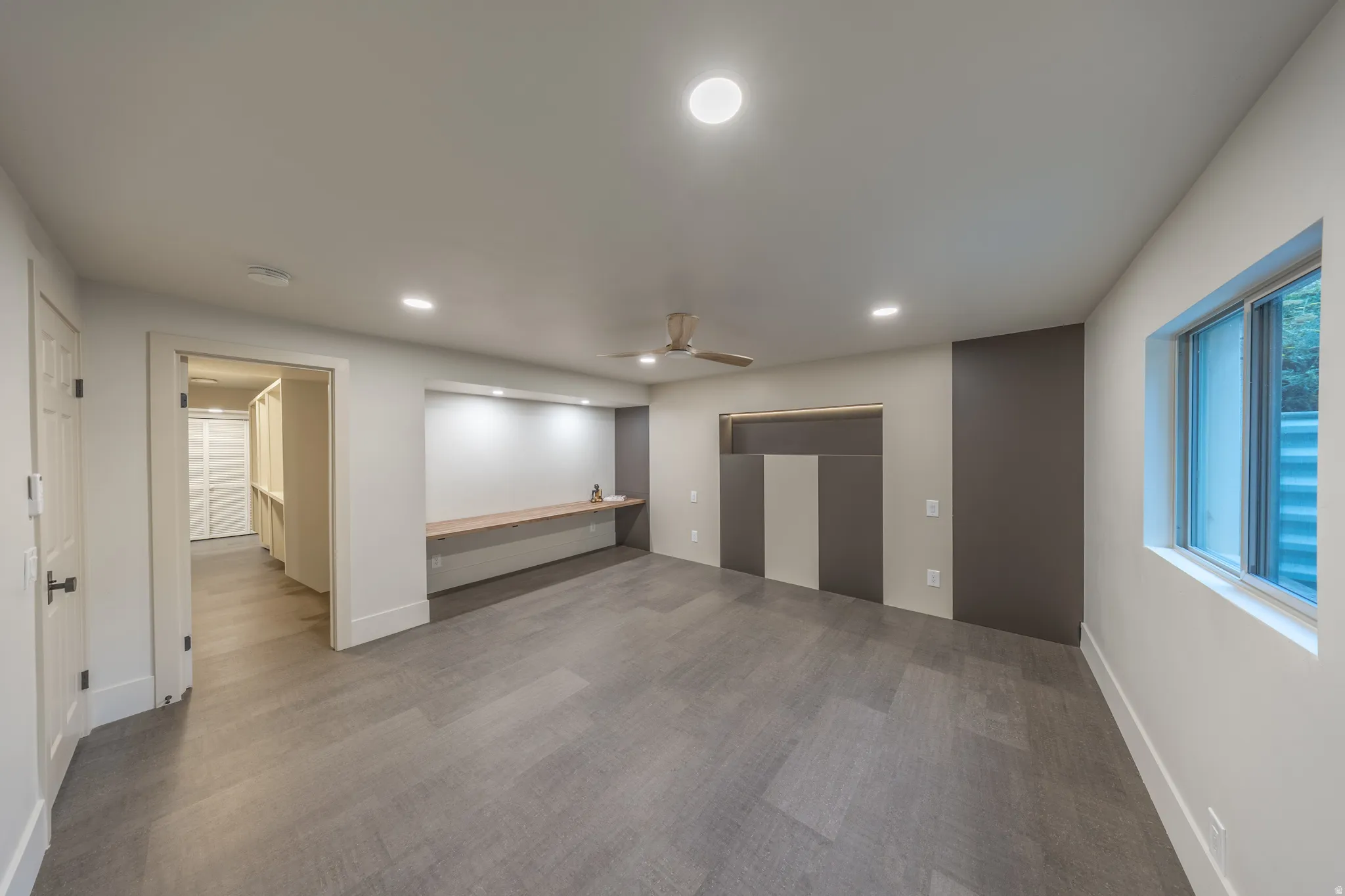 Spacious open-concept living area featuring polished concrete flooring, recessed lighting, and neutral wall finishes