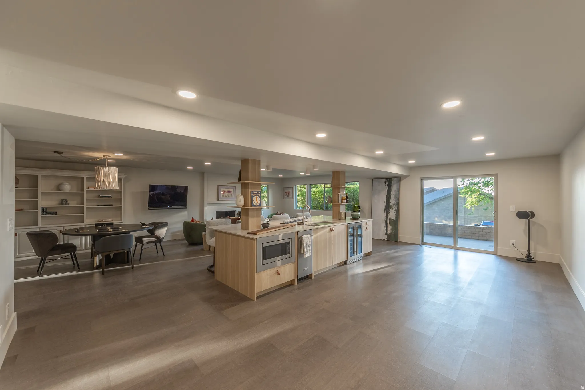 Open-concept living space featuring a wood-finish island with integrated appliances, stainless steel range hood, and ample counter seating