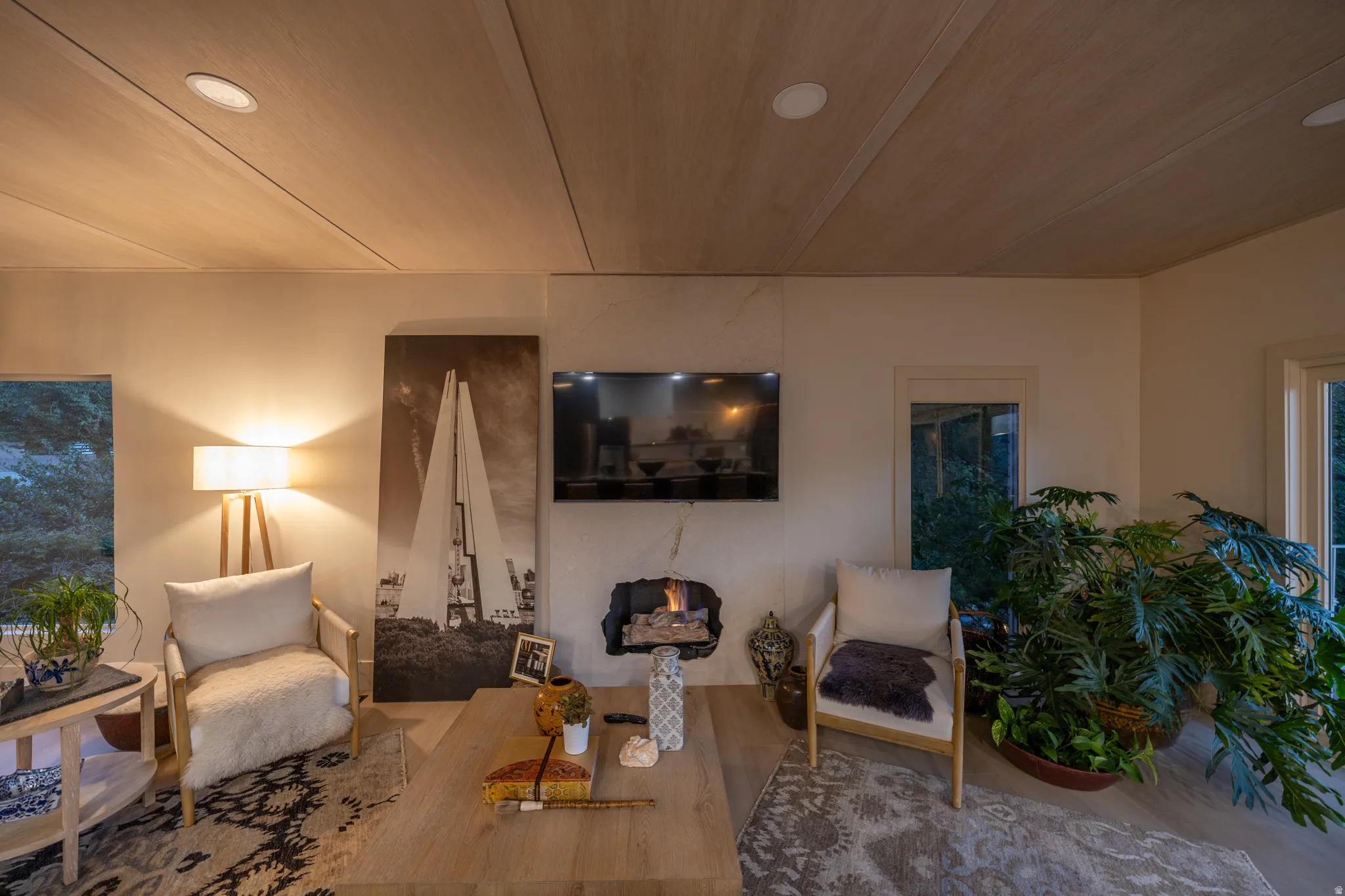 Bright, open living room showcasing warm wood-finish flooring, recessed ceiling lighting, and large windows framing natural light