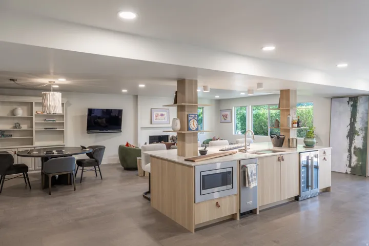 Integrated kitchenette with light wood-finish cabinetry, built-in microwave, and wine refrigerator
