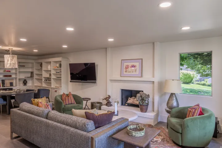Recessed lighting, built-in shelving, fireplace, large window, and wood-finish flooring