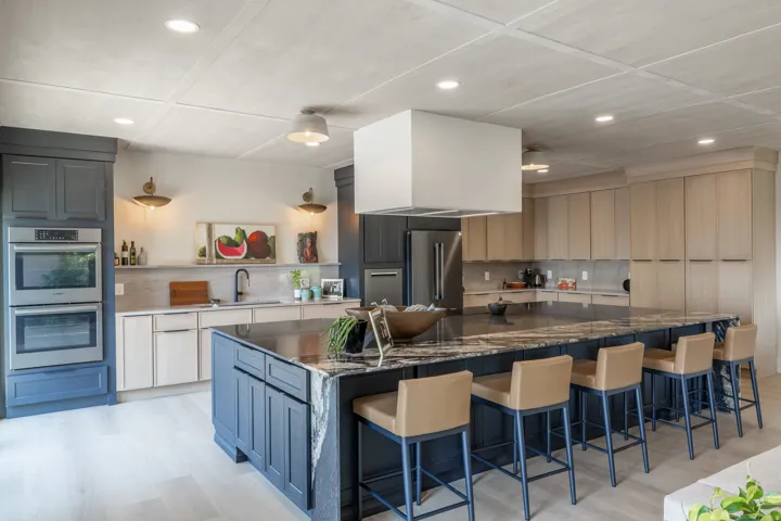 Gourmet kitchen with a large island featuring a waterfall edge, stone countertops, and integrated stainless steel appliances