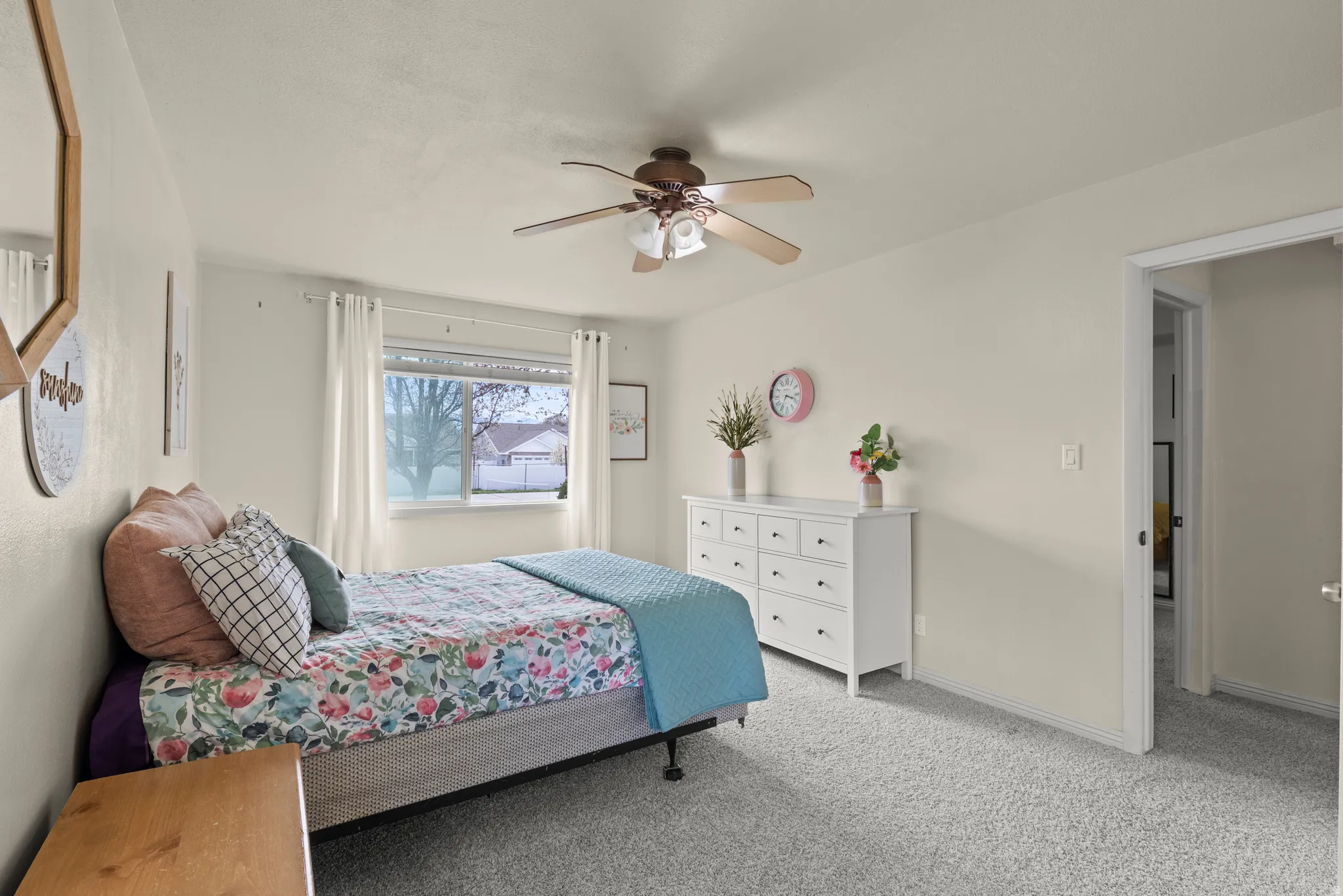 Carpeted bedroom featuring a large window, a ceiling fan with integrated lighting, and neutral wall tones