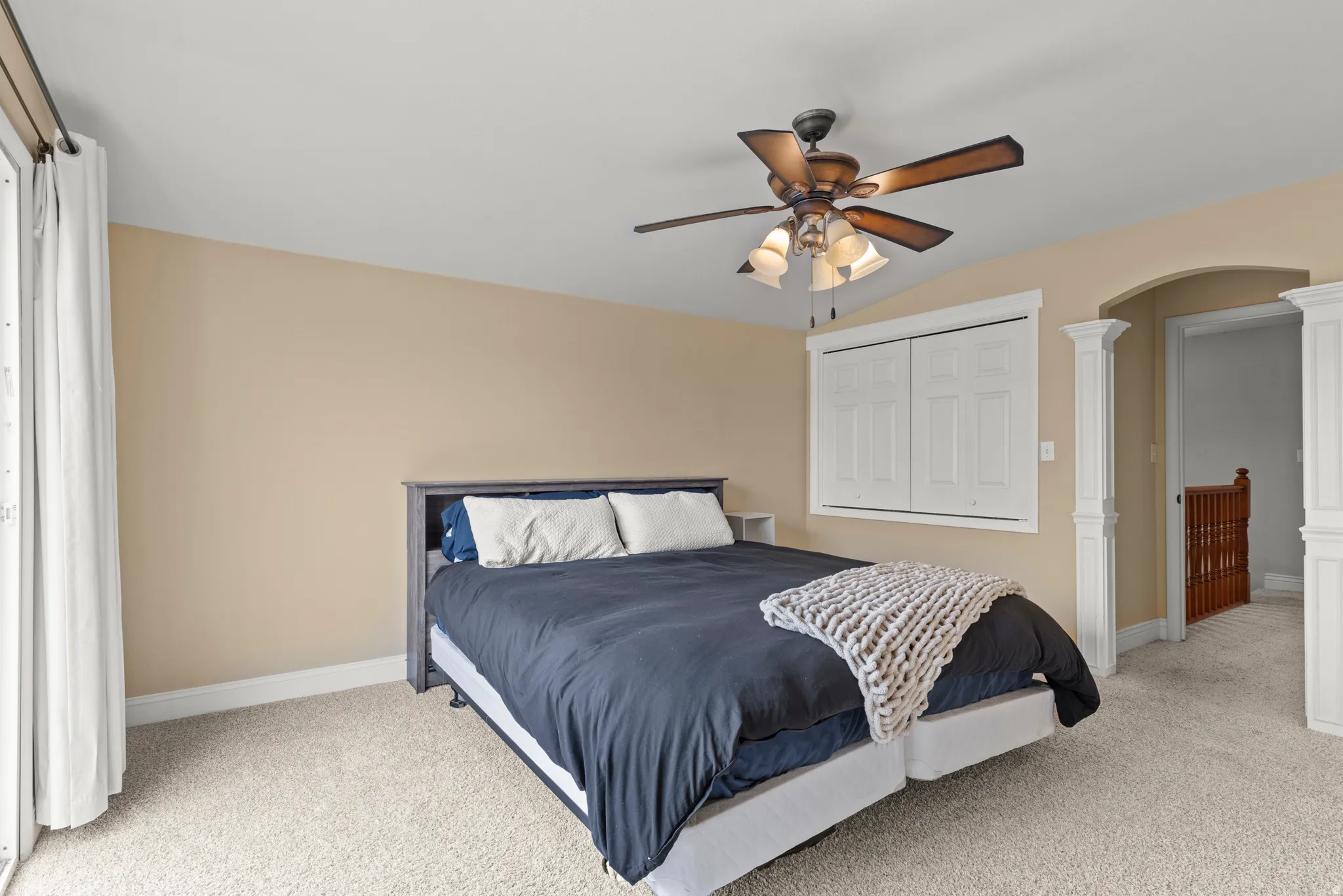 Spacious bedroom featuring neutral wall finishes, carpeted flooring, and abundant natural light from large windows
