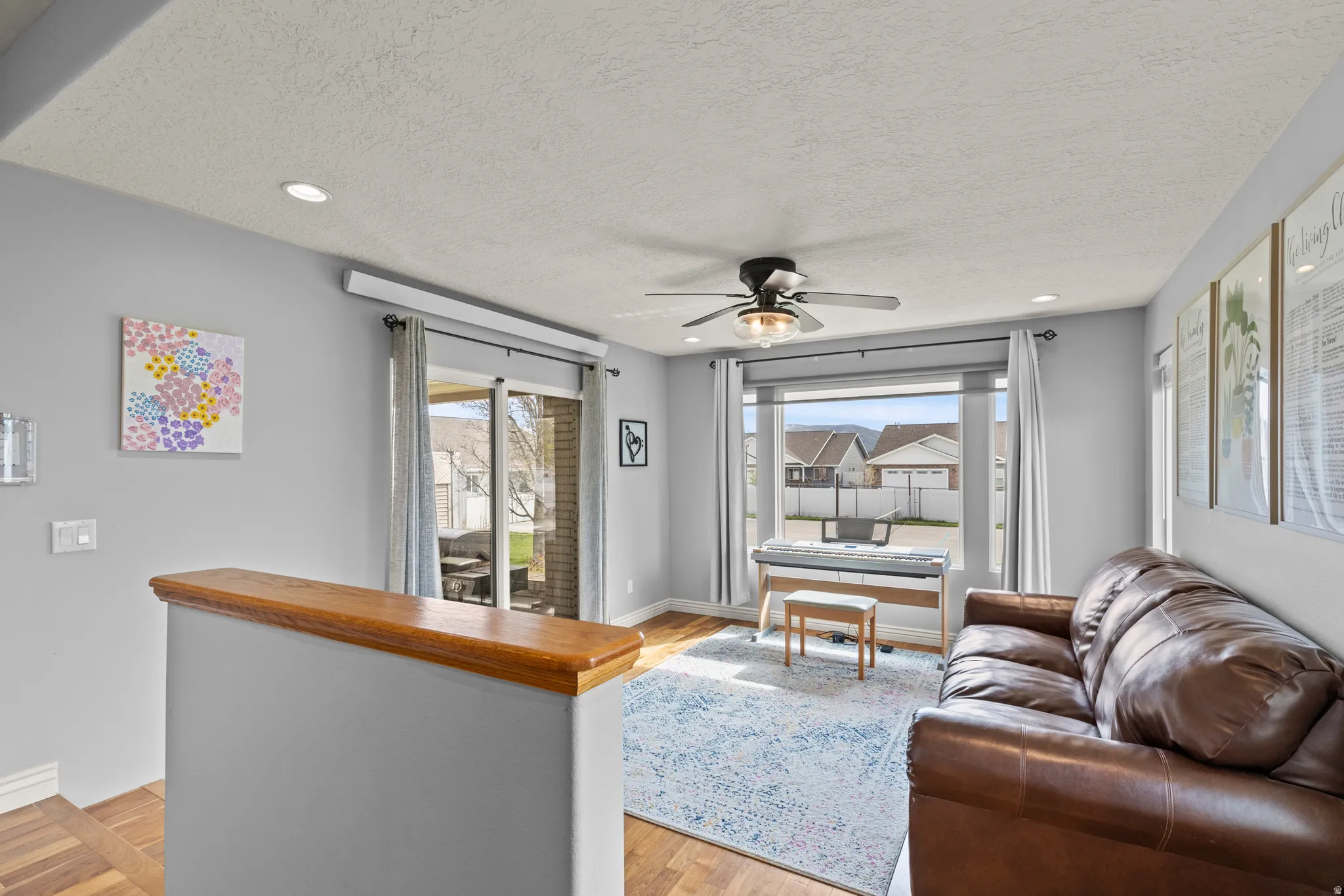 Bright, open living space featuring a wood-finish bar with gray cabinetry, ceiling fan, and recessed lighting