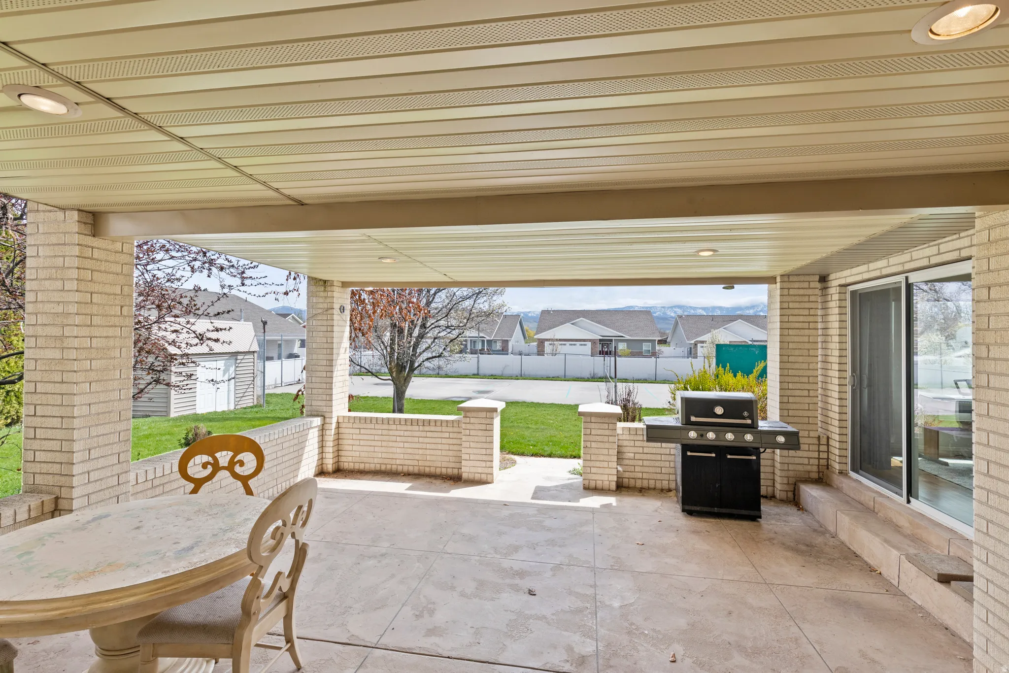 Covered patio featuring a concrete surface, brick construction, and integrated outdoor kitchen with built-in grill