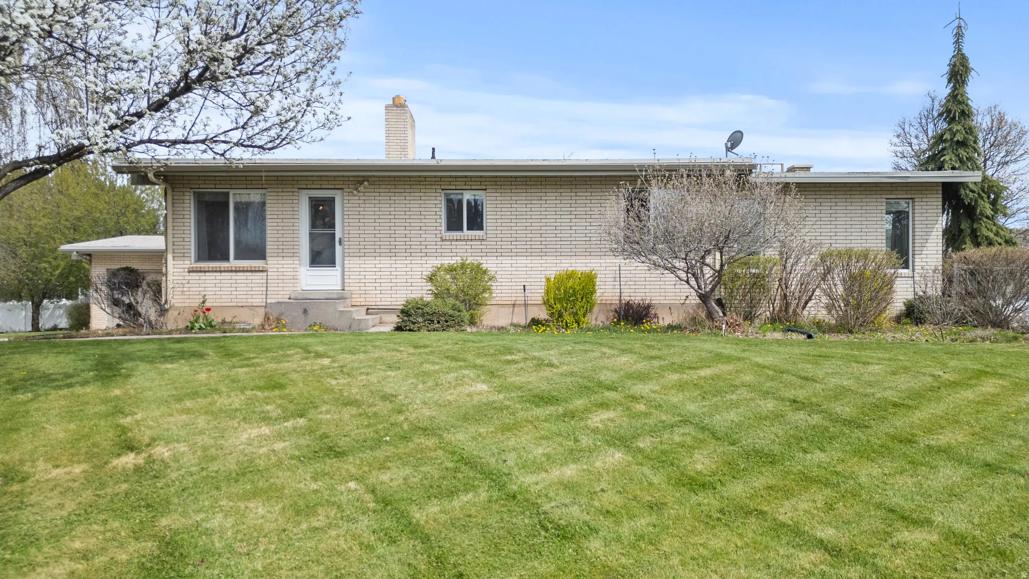 Brick exterior ranch-style home featuring a prominent front lawn