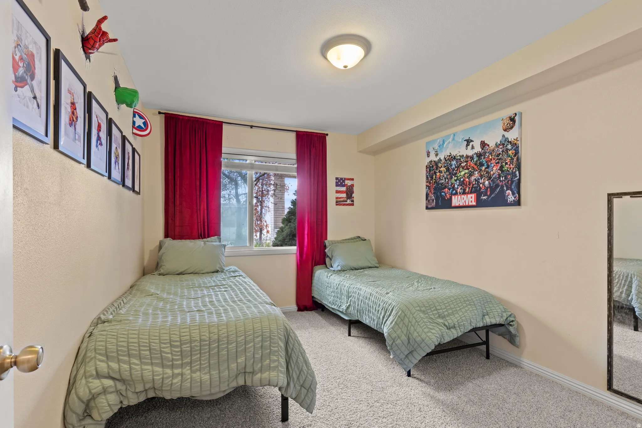 Carpeted room featuring a window with red drapes, a ceiling-mounted light fixture, and light-toned walls