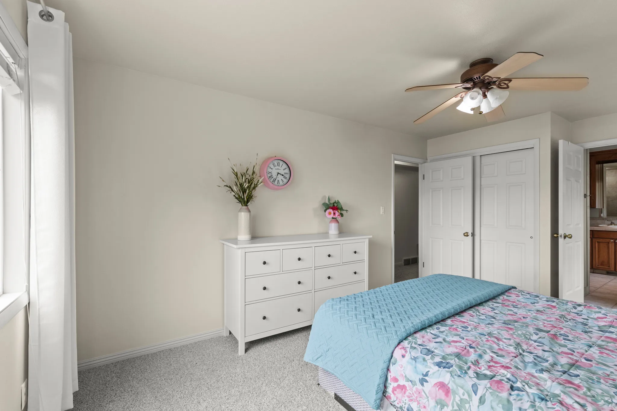 Carpeted room featuring a ceiling fan with integrated lighting, a window with vertical blinds, and a built-in closet with bifold doors