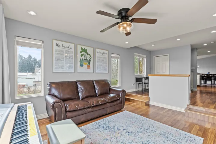 Bright and open living area showcasing hardwood flooring, a leather sofa with nailhead trim, and abundant natural light from multiple windows
